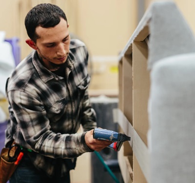 Couch Potatoes upholsterer hand-stretching and stapling fabric onto a sofa frame