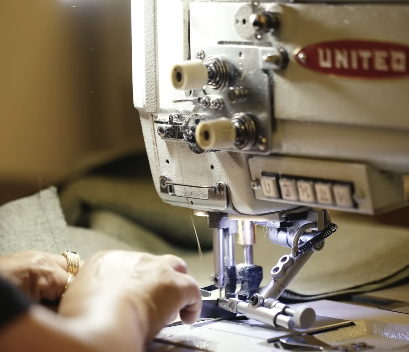 Seamstress sewing a sofa cover on a United industrial machine